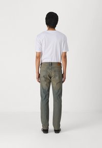 Blå denimjeans med en falmet finish, straight-leg kutt og to baklommer. Parets med en enkel hvit t-skjorte. Svarte sko synlige.