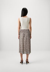 Ribbet, ermeløs hvit topp kombinert med et midilengdes, m�ønstret skjørt i nyanser av beige og grått, med elastisk midje og en subtil glans.