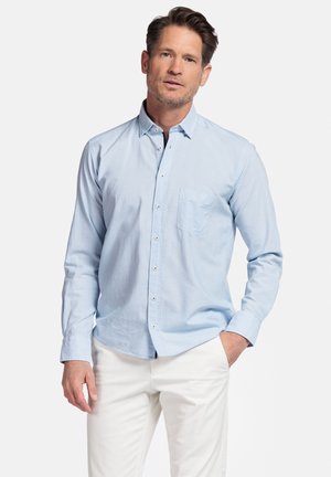 Lichtblauw overhemd met lange mouwen, borstzak en witte knopen. Gekleed met witte broek, met een casual pasvorm.