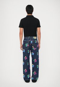 Blugi din denim, cu croială lejeră, având un model grafic multicolor cu recipiente pentru băuturi jucăușe, asortați cu un tricou polo negru.