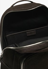 Schwarzer Wildleder-Rucksack mit glattem Innenfutter, Reißverschluss und einer kleinen Tasche mit dem Aufdruck "Massimo Dutti." Minimalistisches Design.