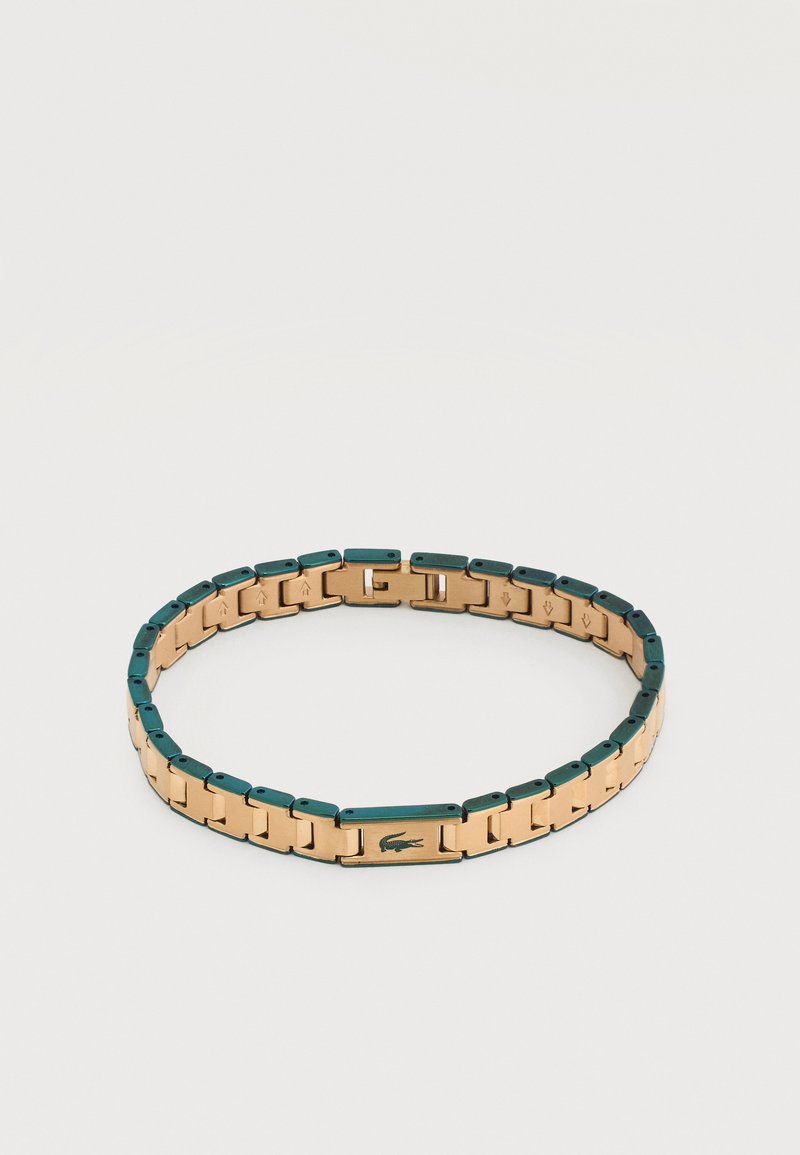 Βραχιόλι από χρυσό και πράσινο μέταλλο με συνδεδεμένους κρίκους και ορθογώνιο κούμπωμα που φέρει μικρό λογότυπο κροκοδείλου.