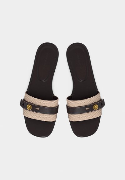 Ζευγάρι μαύρα επίπεδα σανδάλια με μπεζ πλεγμένους ιμάντες και μικρά χρυσά διακοσμητικά κουμπιά σε κάθε ιμάντα, απεικονιζόμενα από πάνω σε λευκό φόντο.