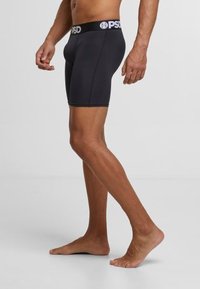 Caleçons de boxe pour hommes noirs avec un design ajusté, une taille élastique arborant le logo "PSD", et un tissu lisse et extensible pour un confort optimal.