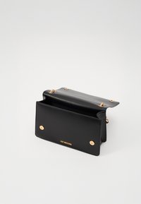 Svart skinnhåndbag med en strukturert design, gullhardwaredetaljer og åpen topp som avslører innvendig plass. Logo vist på fronten.