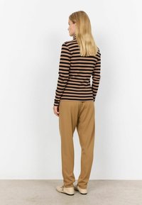 Randig långärmad topp i brun och beige, kombinerad med lösa beige byxor. Slät tyg, avslappnad passform och en enkel design utan utsmyckningar.