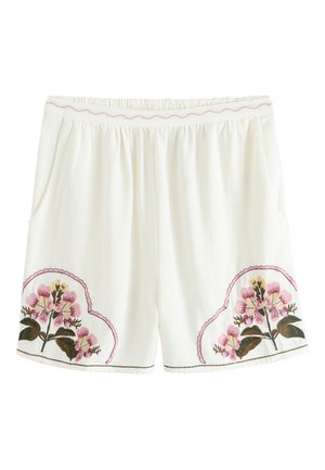 Valkoiset shortsit, joissa joustava vyötärö, sivutaskut ja vaaleanpunainen kukkakirjailu molemmissa lahkeissa lähellä helmaa.