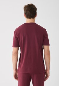 Mørkerød kortærmet T-shirt med rund hals, lavet af blødt bomuld, der har en afslappet pasform og minimal sydetiketter ved kanten.