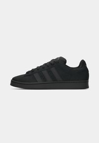 Svarta mocka sneakers med platta snören, tre sidostråk och gummisula. Har en rundad tå och minimala varumärkesdetaljer.