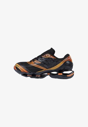 Zapatilla deportiva negra y naranja con parte superior de malla, cierre de cordones y diseño único de entresuela hueca para amortiguación y soporte.