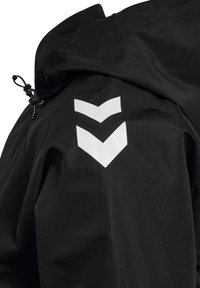 Giacca nera con cappuccio caratterizzata da due strisce a forma di chevron bianche sulla parte superiore della manica e da un cordino regolabile vicino al colletto.