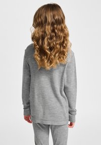 Grau langärmeliges Oberteil aus weichem, strukturiertem Stoff, mit relaxed Fit und gerippten Bündchen, kombiniert mit passenden grauen Hosen.