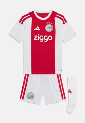Ajaxin jalkapallopaita, jossa punainen keskilinja valkoisessa paidassa, valkoiset shortsit, joissa punaiset raidat, ja valkoinen sukka punaisella logolla.