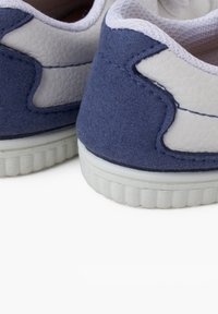 Sneaker in suede blu e pelle bianca con una finitura testurizzata e suole in gomma, caratterizzati da cuciture a contrasto e una forma arrotondata.