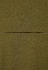 Tkanina w kolorze oliwkowym o gładkiej fakturze z poziomym szwem na środku. Materiał wydaje się elastyczny i miękki.