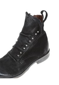 Bottine noire en daim à finition texturée, ornée de clous métalliques le long de la couture latérale et dotée d'un petit talon en bois.