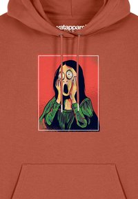 Roestkleurige hoodie met een afgedrukte afbeelding van een persoon met grote ogen en een open mond, geframed tegen een rode achtergrond.