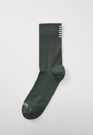 Grønn ankelstrømpe laget av teksturert stoff med ribbestrikket mansjett. Har et ensfarget design og stripete detaljer øverst.