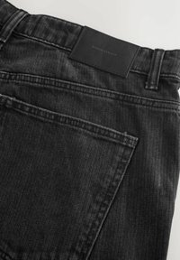 Černé džíny z denimu s texturovaným povrchem, koženou etiketou na pásu a klasickým designem kapes se jemnými švy.