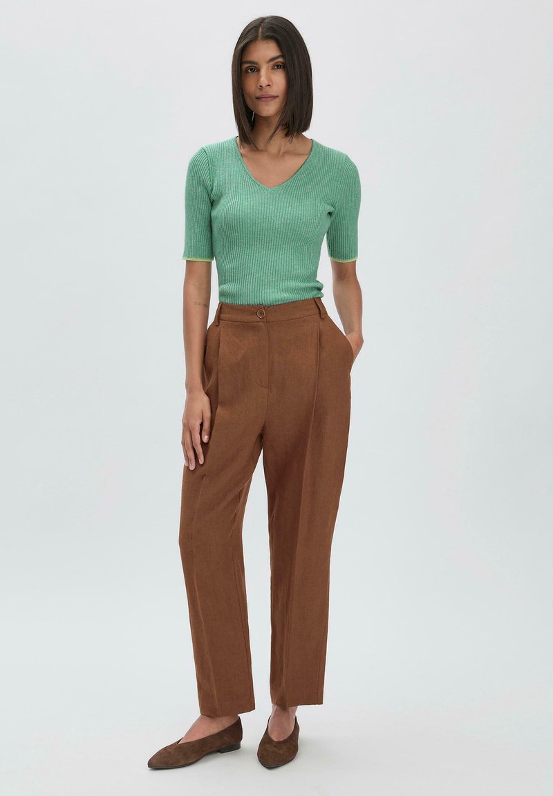 Mintgroene, korte mouwen, geribbelde top gecombineerd met hooggepaste, rechte bruine broek. Bruine, puntige ballerina's maken de outfit compleet.