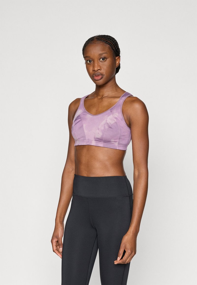 Μωβ αθλητικό σουτιέν με στρογγυλή λαιμόκοψη, φαρδιές τιράντες και εφαρμοστή σχεδίαση. Φορεμένο με μαύρο κολάν ψηλής μέσης. Ομαλή υφή, ελάχιστες ραφές.