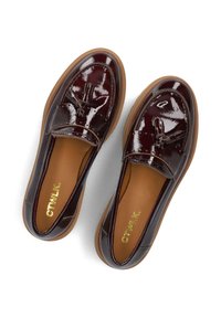 Burgundy patent leather loafers with a smooth finish, featuring a tassel accent and a contrasting brown rubber sole. Gold logo inside.