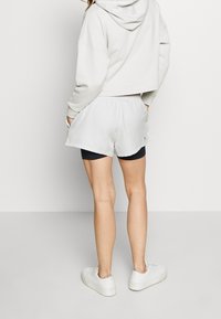 Sudadera corta gris claro combinada con pantalones cortos cargo blancos y holgados. Tejido suave, cinturilla elástica y bolsillos laterales. Se lleva con zapatillas blancas.