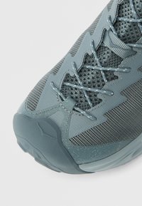 Αθλητικό παπούτσι ανοιχτού γαλάζιου χρώματος με διχτυωτό και συνθετικό υλικό, διακοσμημένο με υφές, σύστημα σταυρωτού κορδονιού και μαλακή σόλα.