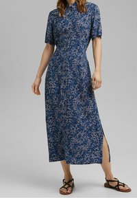 Robe midi fleurie bleue avec manches courtes, col boutonné et fentes latérales. Fabriquée en tissu léger, avec un motif texturé.