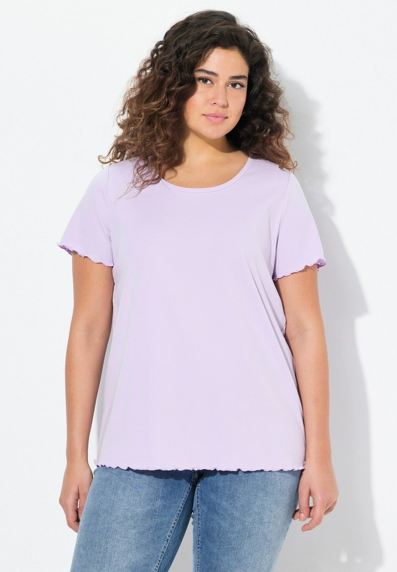 Camiseta corta de manga corta de color púrpura claro con bordes ondulados, escote redondo y un corte relajado, combinada con jeans de color azul claro.