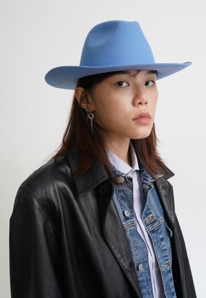 Light blue felt cowboy hat with a wide brim. Worn with a black leather coat and denim jacket, featuring buttons and a striped shirt underneath.