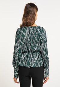 Grøn mønstret bluse med lange ærmer, der har et kædedesign og en rynket talje. Fremstillet af glat stof med en afslappet pasform.