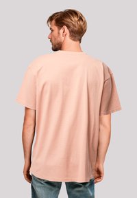 Short-sleeve, oversized t-shirt in light peach cotton. Simple design with a round neckline and straight hem, showing a smooth texture.