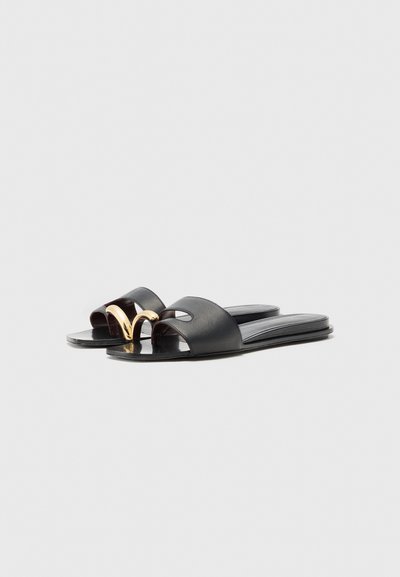 Sandales en cuir noir à enfiler avec un design ouvert à l'avant, présentant un accent doré sur les sangles et une semelle plate pour le confort.