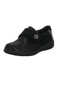 Black shoe featuring a textured surface with a smooth suede strap, circular metallic button, and a low, cushioned sole.