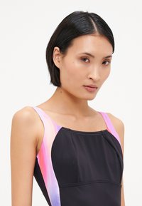 Maillot de bain noir avec un design dégradé rose et violet sur les bretelles, texture lisse et coupe ajustée et profilée.
