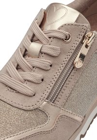 Sneaker beige chiaro con tomaia in suede, dettagli metallici decorativi, chiusura con zip e pannello in tessuto testurizzato. Lacci rotondi nello stesso colore.