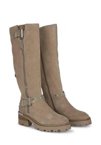Botas de ante beige hasta la rodilla con cremallera lateral, detalles en hebilla metálica y tachuelas en la correa, con una suela texturizada.