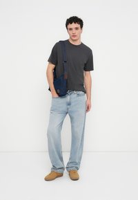 Γκρι κοντομάνικη μπλούζα, ανοιχτό μπλε φαρδιά τζιν, καφέ σουέντ παπούτσια και τσαντάκι ώμου από τζιν με ταμπά δερμάτινη λεπτομέρεια.