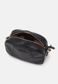 Borsa cosmetica nera in pelle con dettagli in metallo dorato e logo impresso. Presenta una forma rettangolare e una texture liscia.