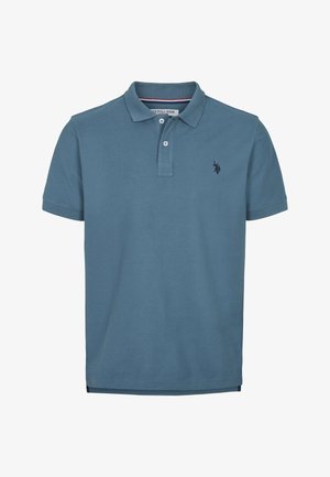 Šviesiai mėlynos medvilnės polo marškinėliai. Turi ribotą apykaklę, trijų mygtukų užsegimą ir mažą tamsų logotipą kairėje krūtinės pusėje.