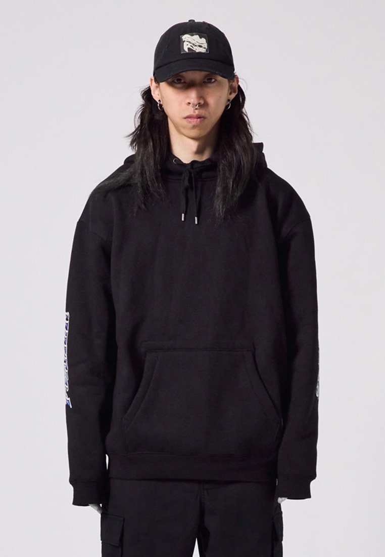 Black hoodie with a kangaroo pocket, drawstrings, and graphic detail on the left sleeve. Paired with a black cap featuring an embroidered logo.