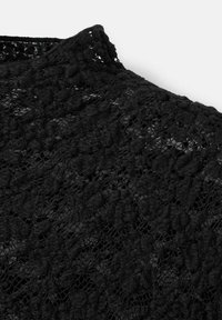 Černá krajková látka má jemný květinový vzor s vyvýšenými texturami. Materiál má měkkou, průhlednou kvalitu a hladký povrch.