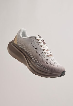 Jasnoszary i beżowy sportowy but do biegania z siateczkową cholewką, białymi sznurowadłami oraz grubą, amortyzowaną brązową podeszwą z napisem "Freeform".