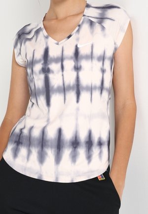 Woman wearing a short-sleeve, V-neck, black and white tie-dye Nike shirt with a small swoosh logo on the chest.