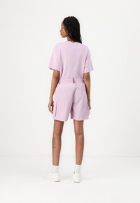 Lila Baumwoll-T-Shirt mit kurzen Ärmeln, kombiniert mit passenden Shorts mit elastischem Bund und Seitentaschen. Uni-Farbe, lässiges Design.