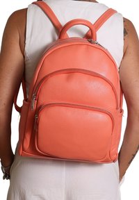 Zaino in pelle corallo con finitura testurizzata, tasche con doppia zip e spallacci regolabili. Dotato di manico superiore per un facile trasporto.