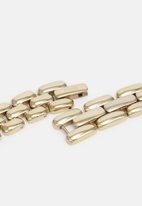 Gold-toned metal bracelet with smooth, rounded links. Features a secure clasp and embossed "FOSSIL" logo on the closure.