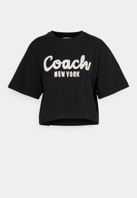 Zwarte cropped t-shirt van katoen, met grote witte tekst "Coach New York" op de voorkant en korte mouwen. Gladde textuur.