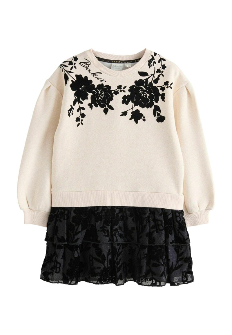 Langärmliges cremefarbenes Sweatshirt mit schwarzem Blumendruck und Puffärmeln, kombiniert mit einem schwarzen, gerafften Rock aus transparenter Stoff.